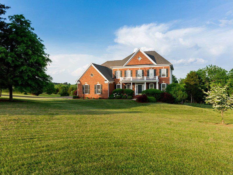 A large brick house sitting on top of a green field.